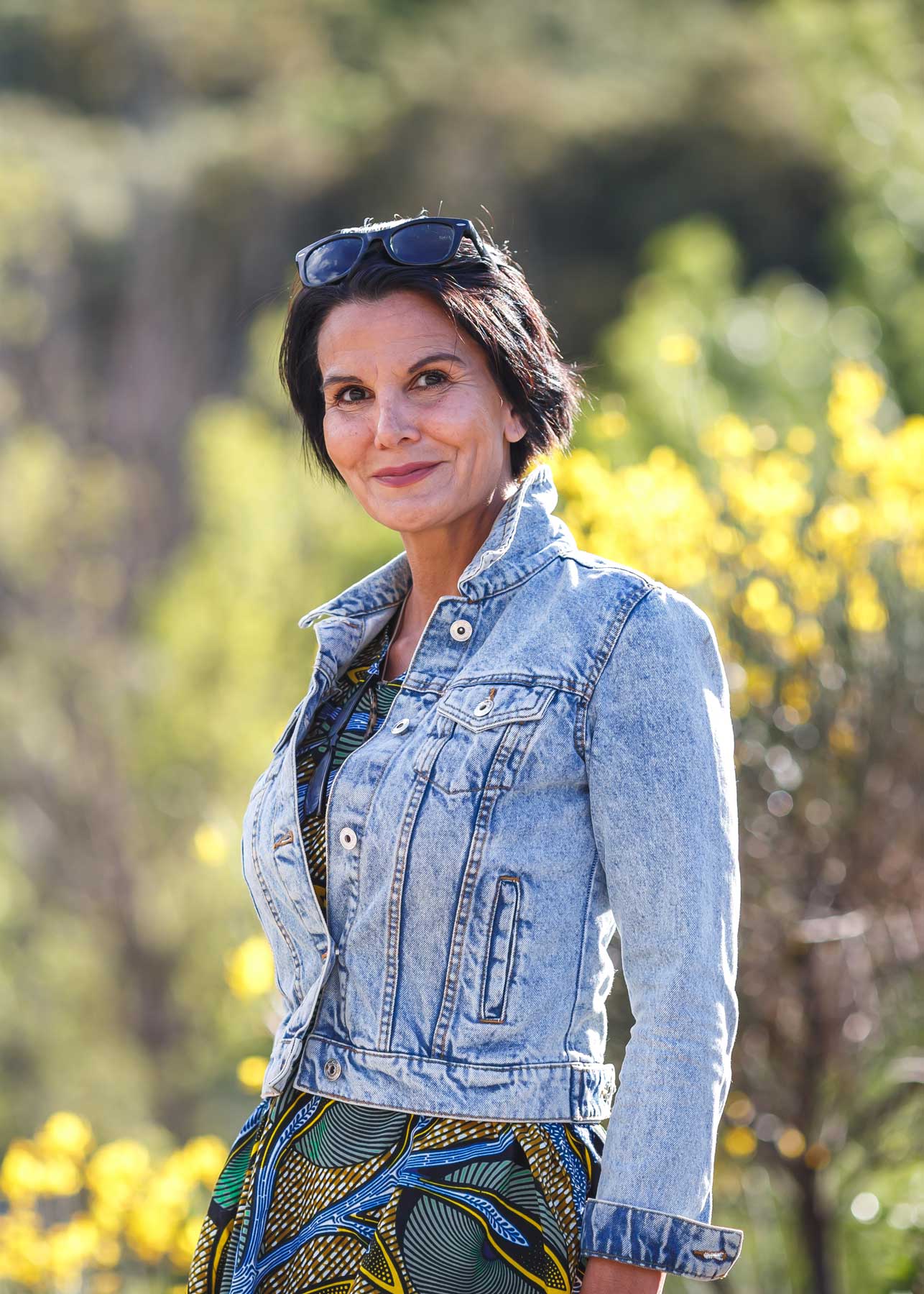 Woman in a denim jacket standing outdoors in warm evening light