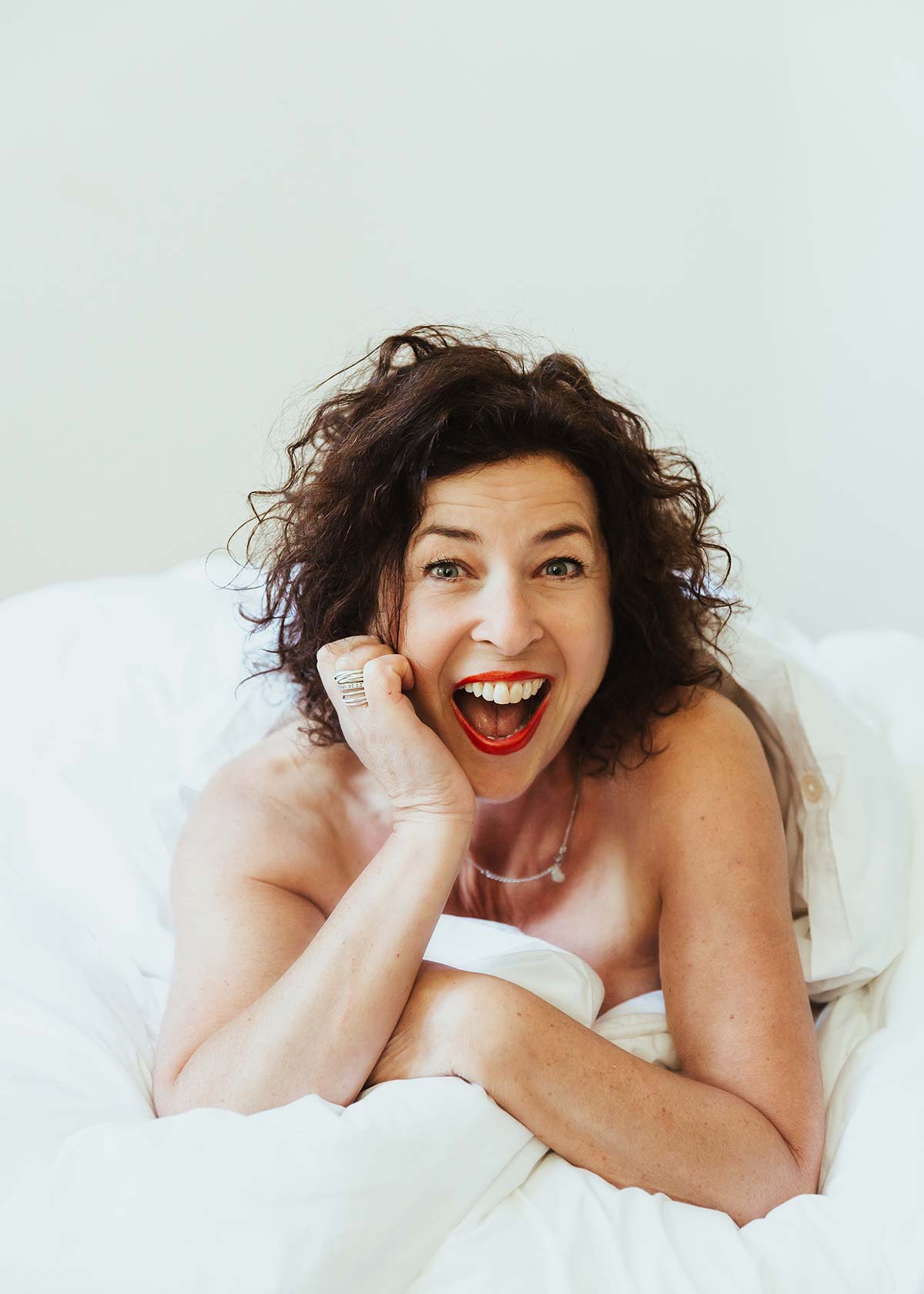 Woman laughing in a bright bedroom portrait