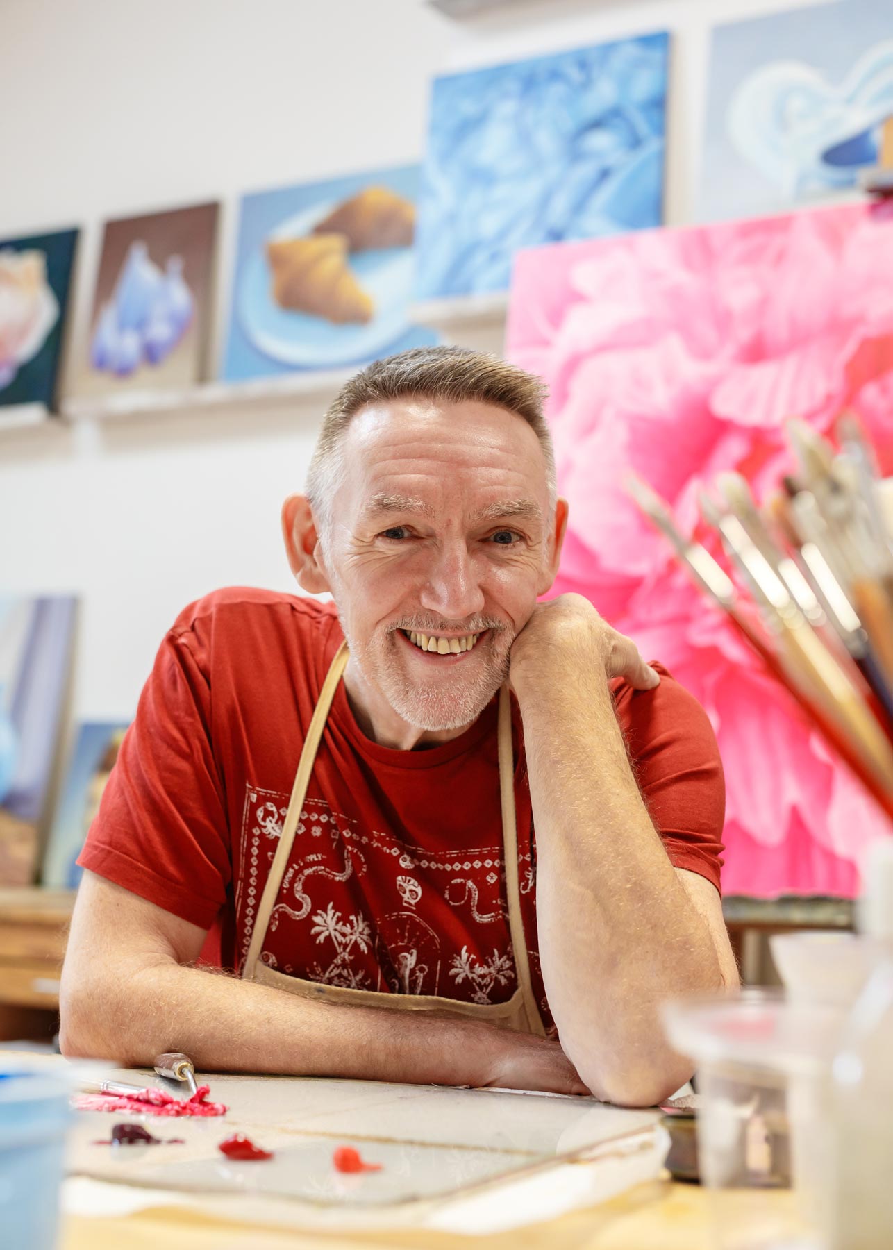 Smiling man seated at a table in a colourful workspace
