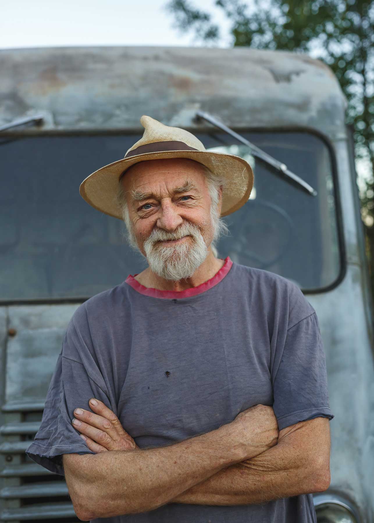 Bearded man in a wide-brimmed hat standing beside a vehicle