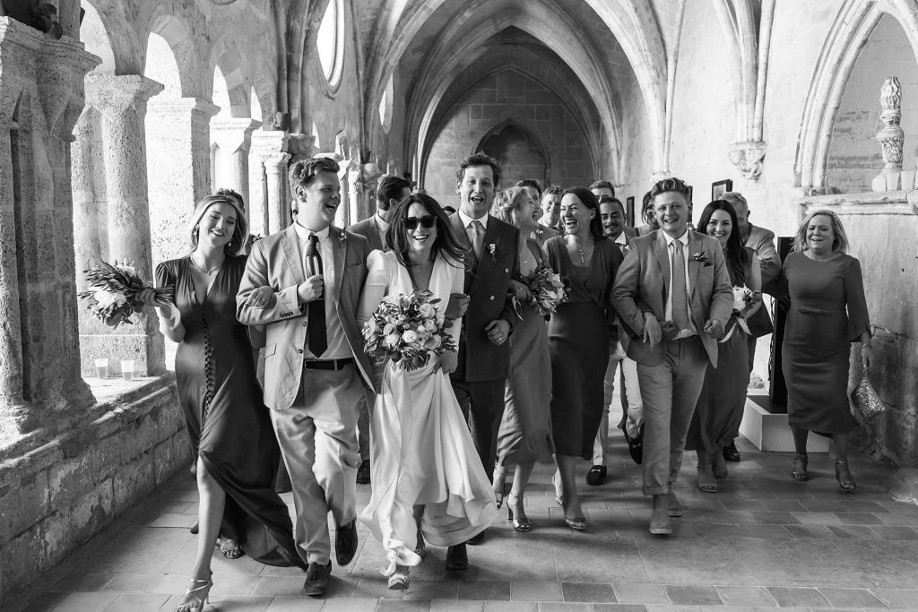 Newlyweds and guests walking and laughing at an Abbaye de Valmagne wedding