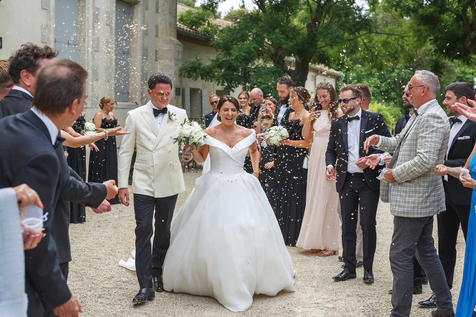 Newlyweds walking through confetti as their guests celebrate at a South of France wedding