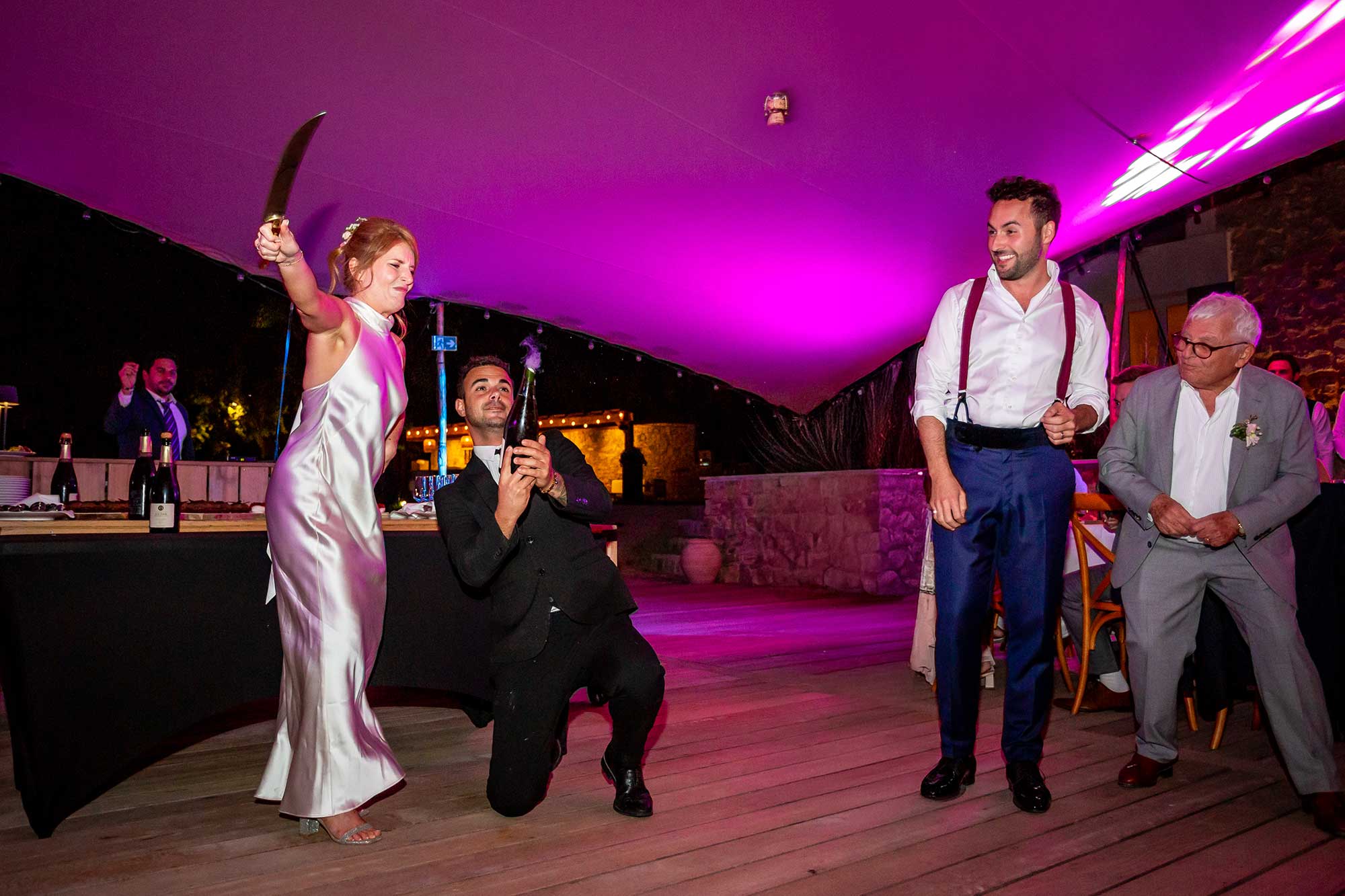 Bride opens champagne using sword at Domaine de Noé wedding