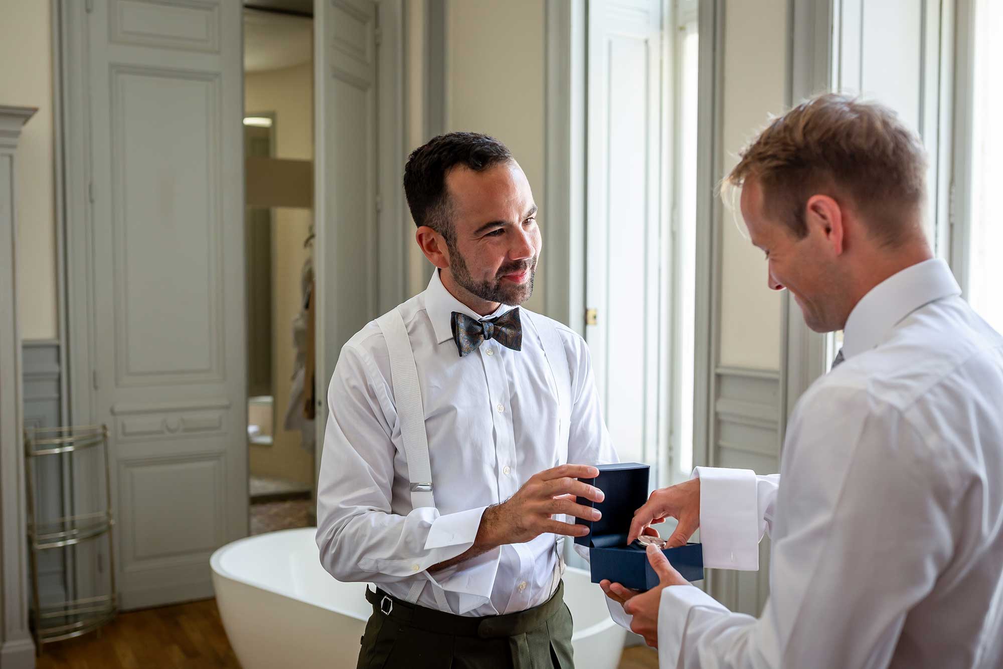 One groom gives the other a gift at Chateau Carrasses vineyard wedding 