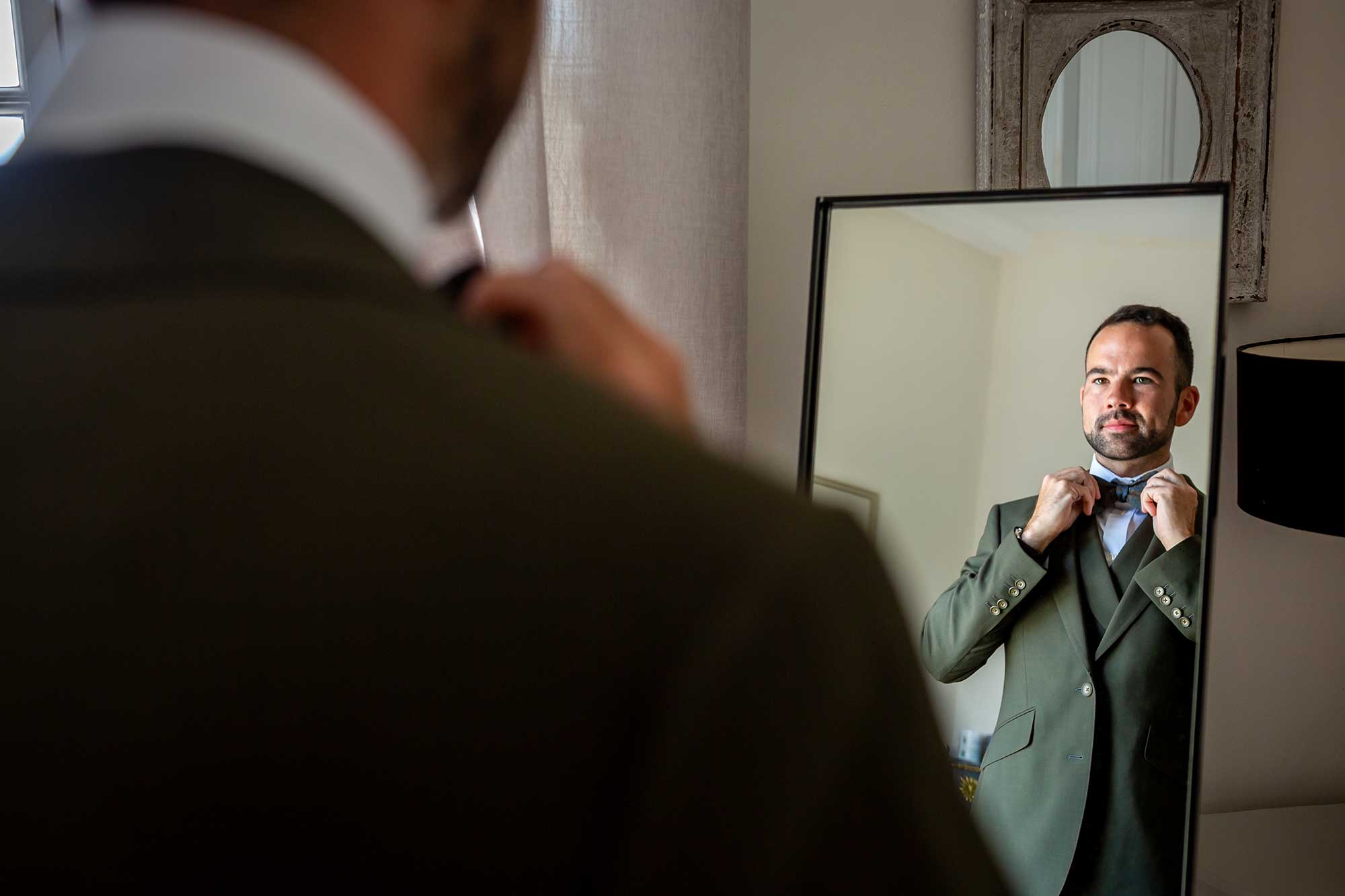 One of the grooms adjusts his bow tie at Chateau Carrasses vineyard wedding 