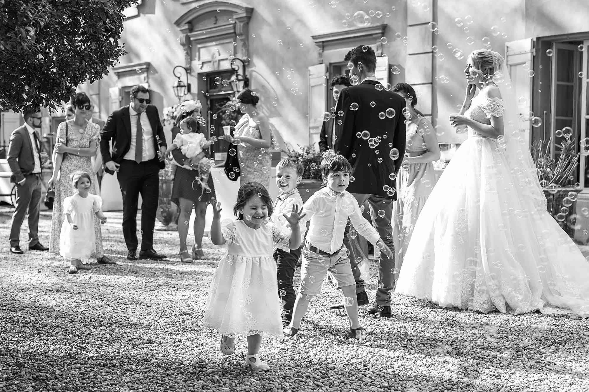 Children running throw bubbles at wedding