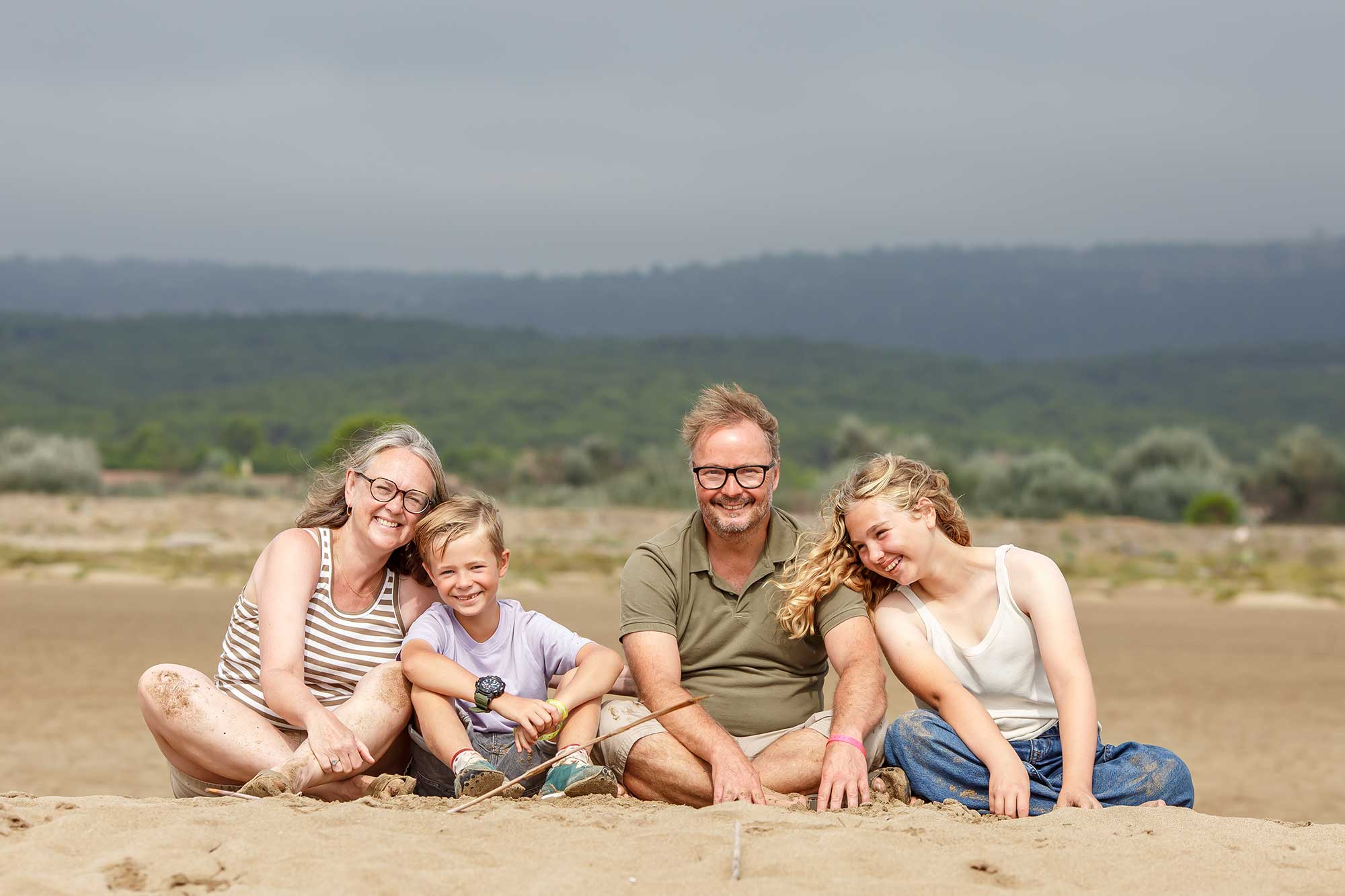 Family of four sitting together on a beach