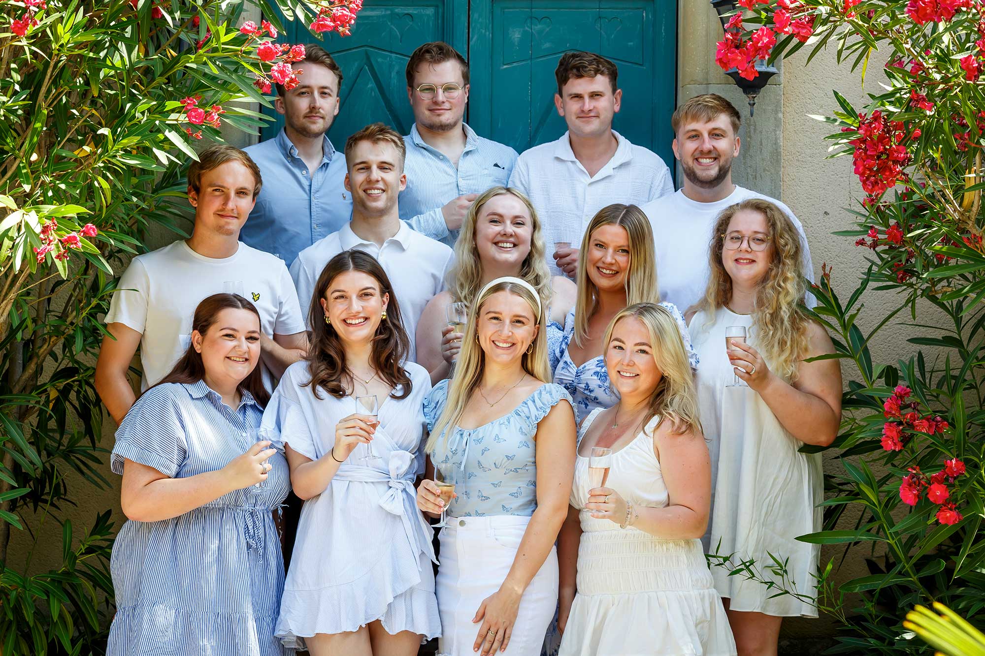 Large family group standing together in front of flowering greenery