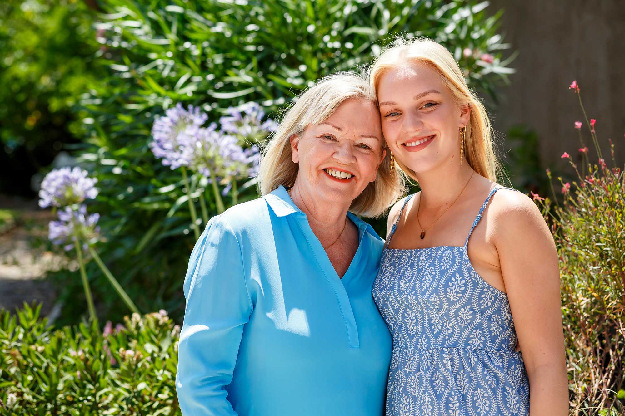 Older woman and teenage girl smiling together in a garden