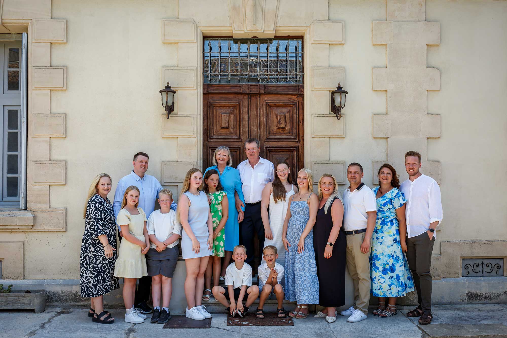 Large multi-generational family group photographed outside a house