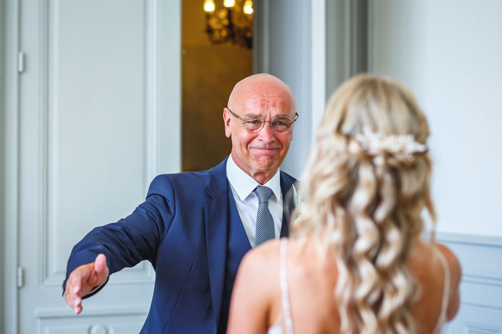 Wedding photojournalist picture of the Dad seeing the bride for the first time with tears in his eyes.