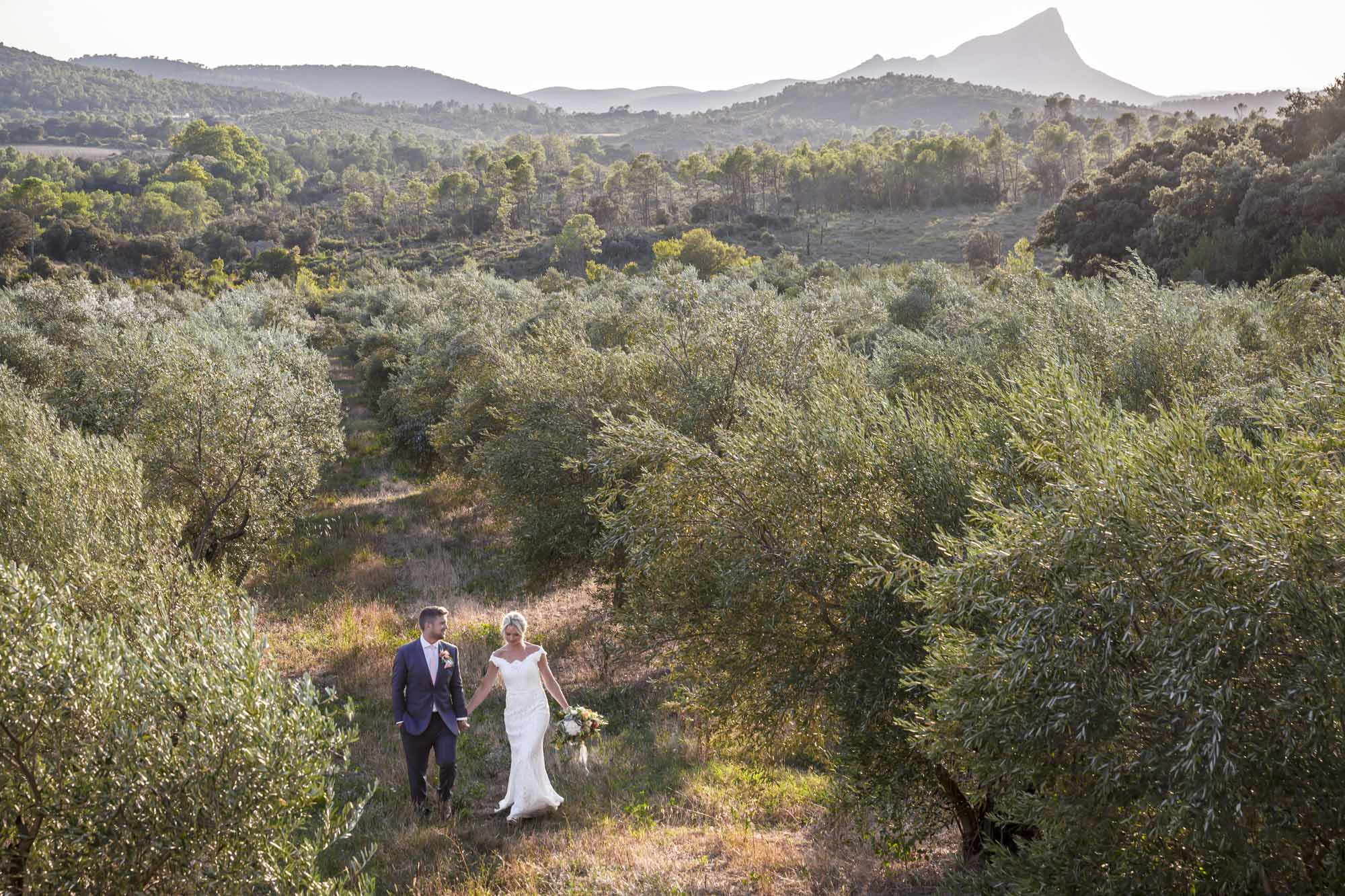 Newlyweds walking through olive groves beneath Pic Saint-Loup in Hérault