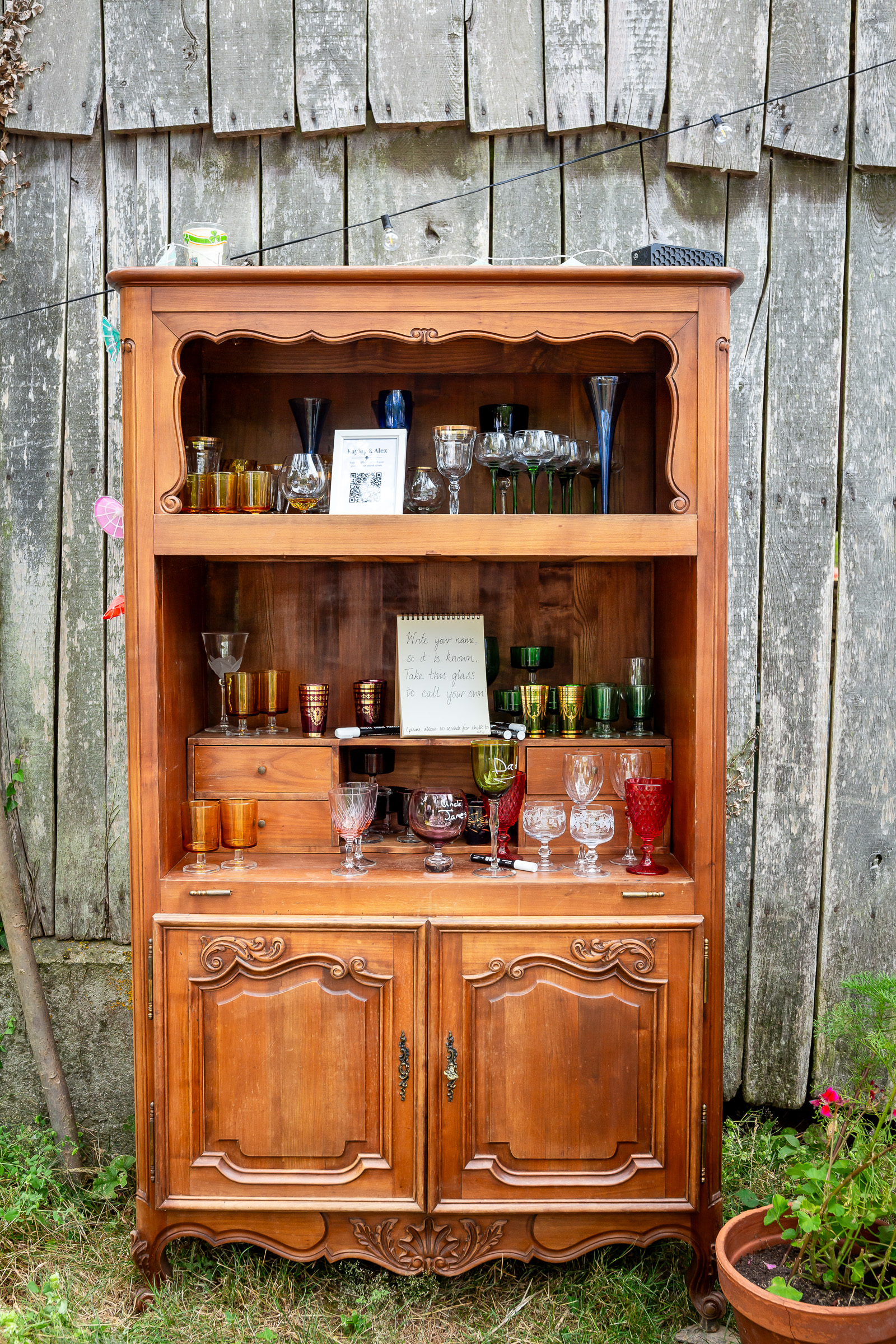 An old French dresser filled with mismatched glasses for wedding guests