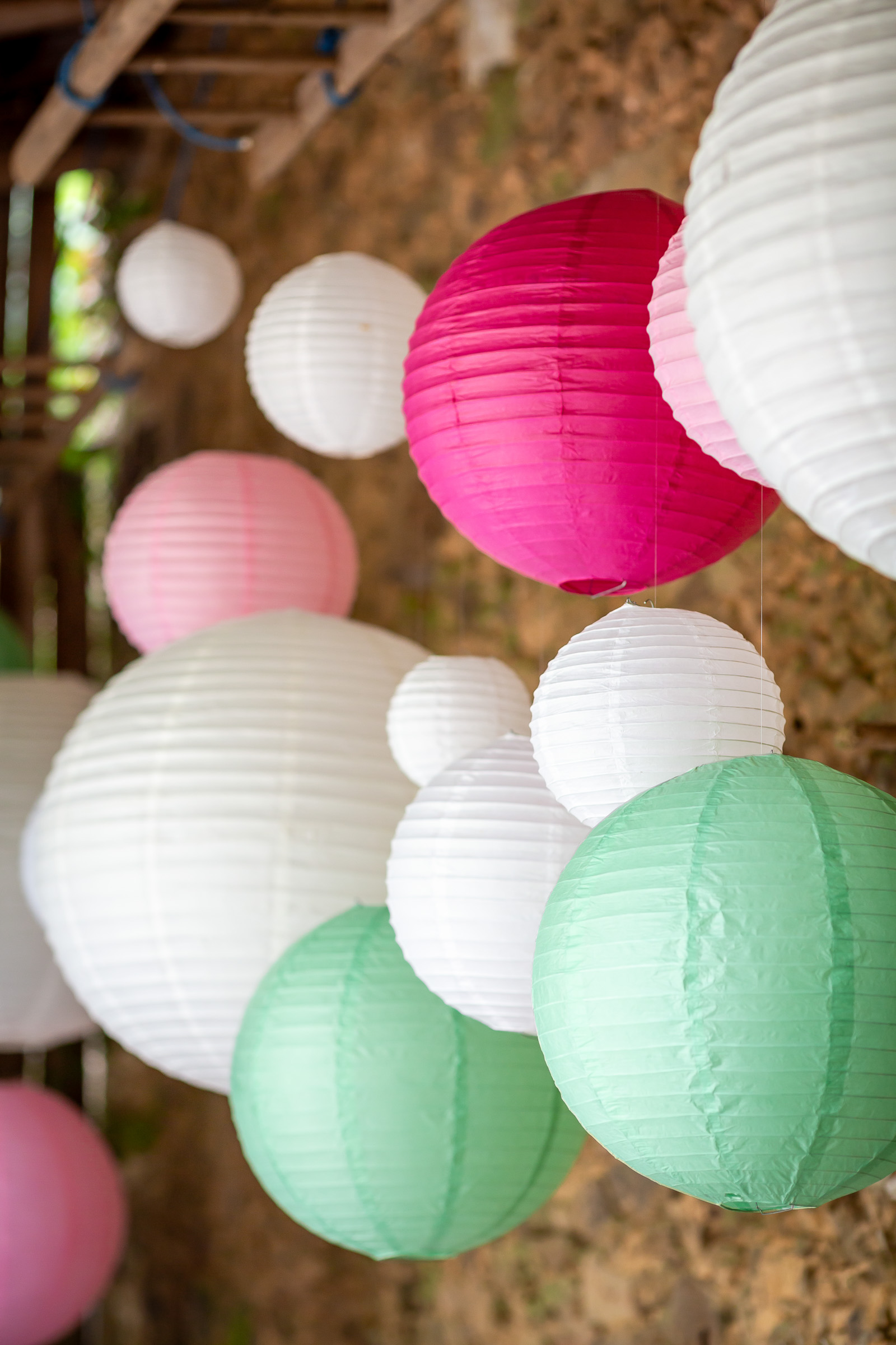 Pink, white and green paper lanterns inside the barn