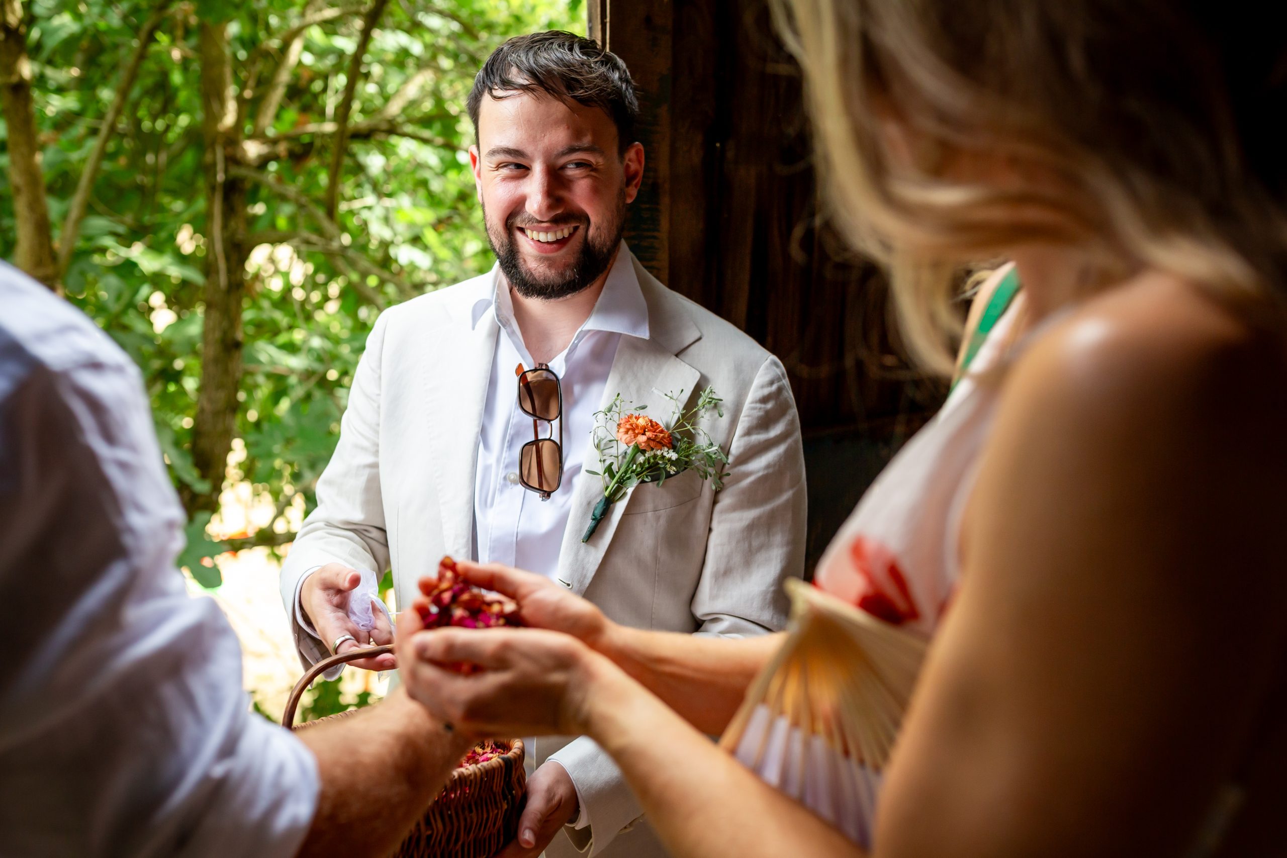 Dried-flower confetti being handed to wedding guests outside the barn