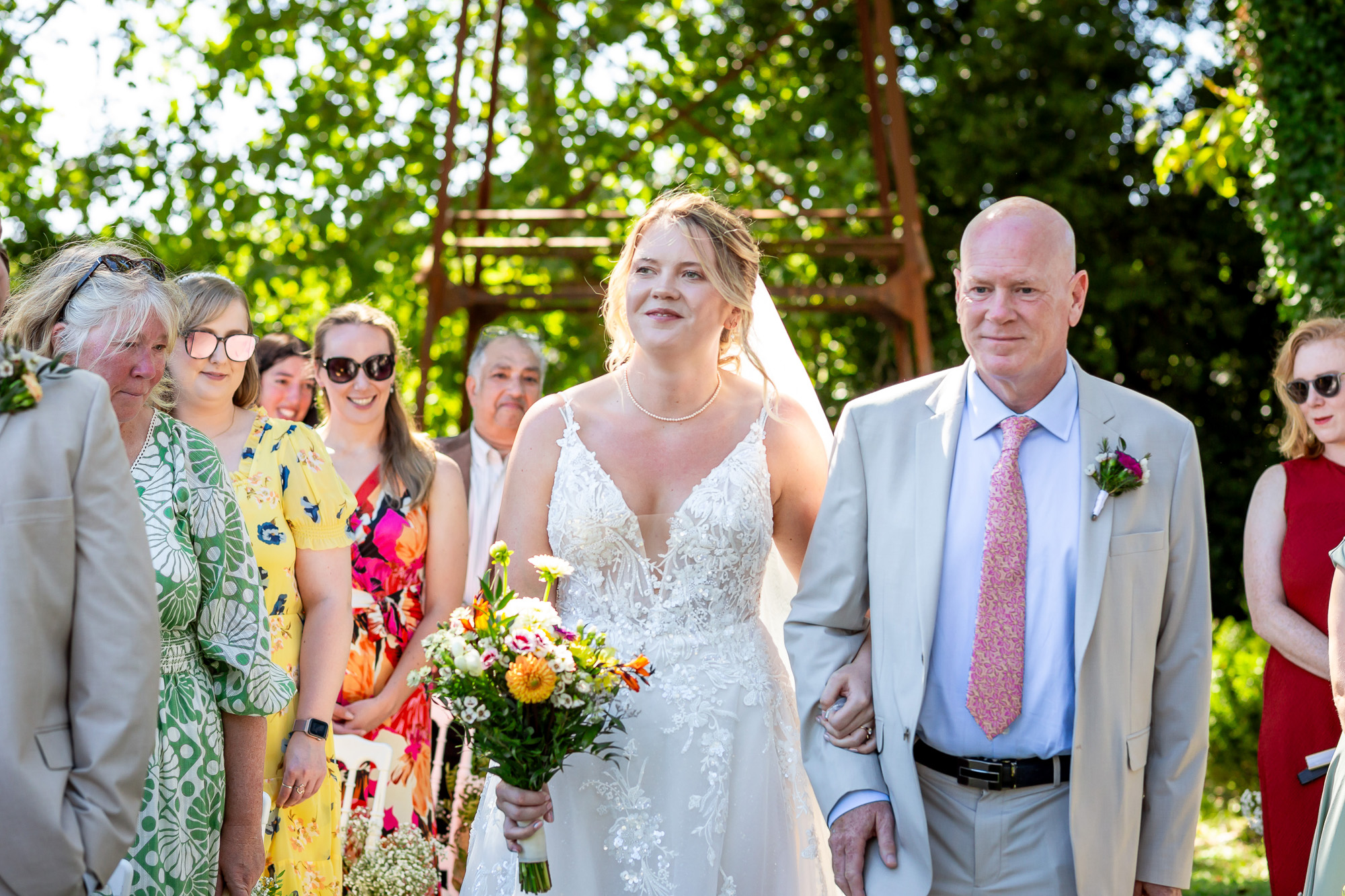 Hannah walking into the outdoor ceremony with her father