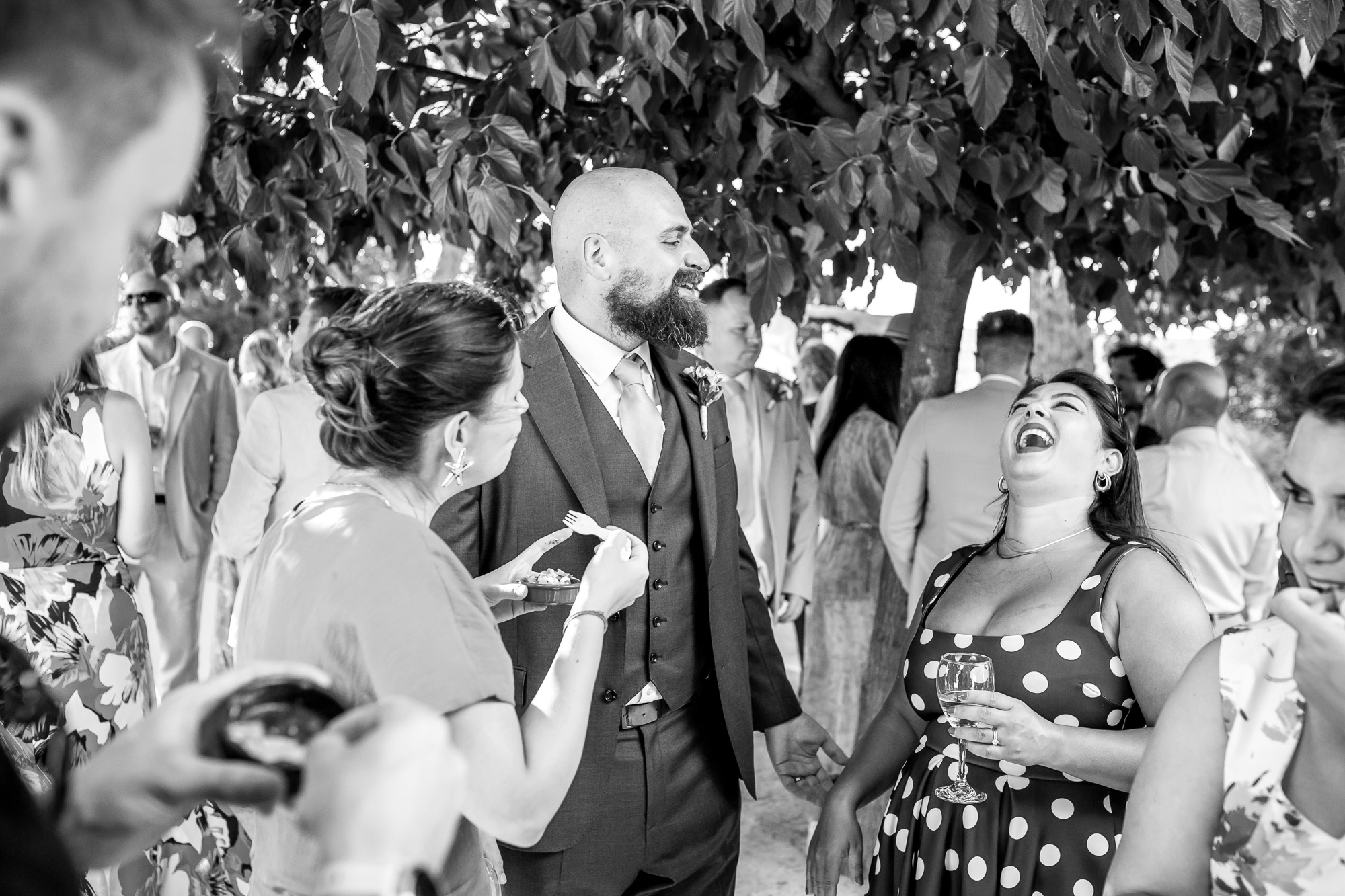 Hannah and Thomas laughing with a guest during the shaded drinks reception