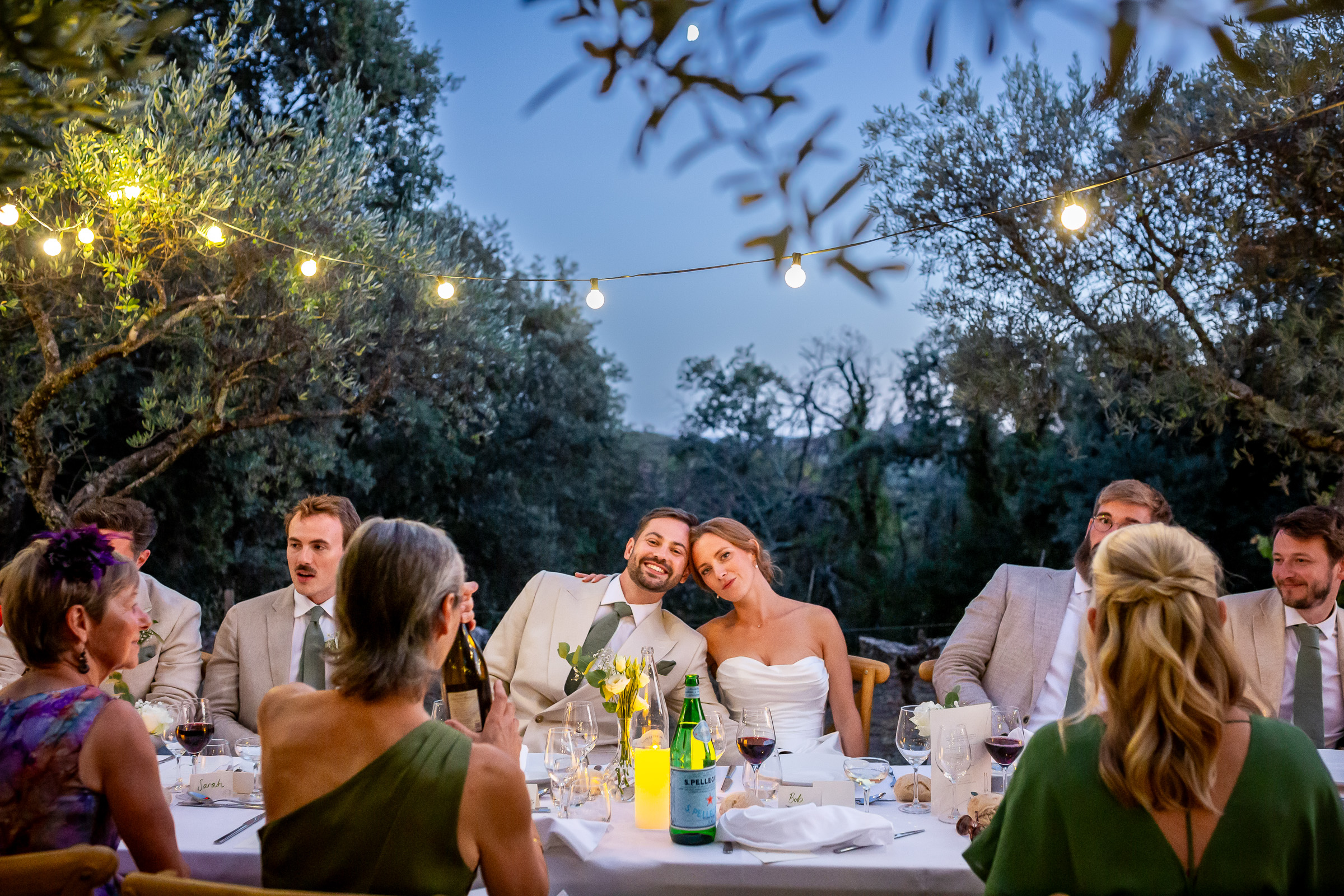 Guests reacting during the wedding speeches beneath the olive trees