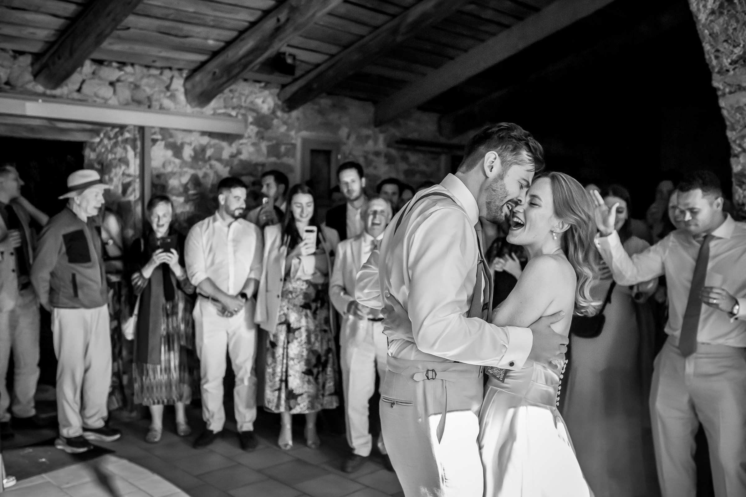 Black and white first dance photograph surrounded by wedding guests